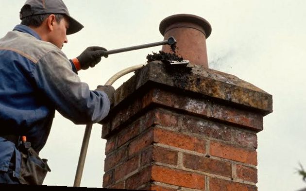 Technician clearing buildup from a chimney crown and pot