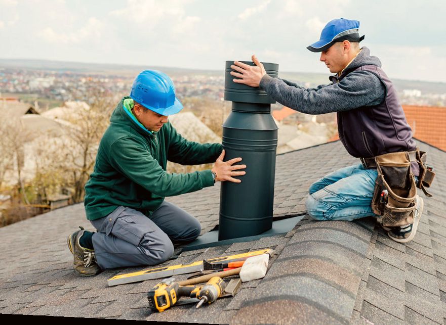 Two technicians setting a new metal flue system on a roof