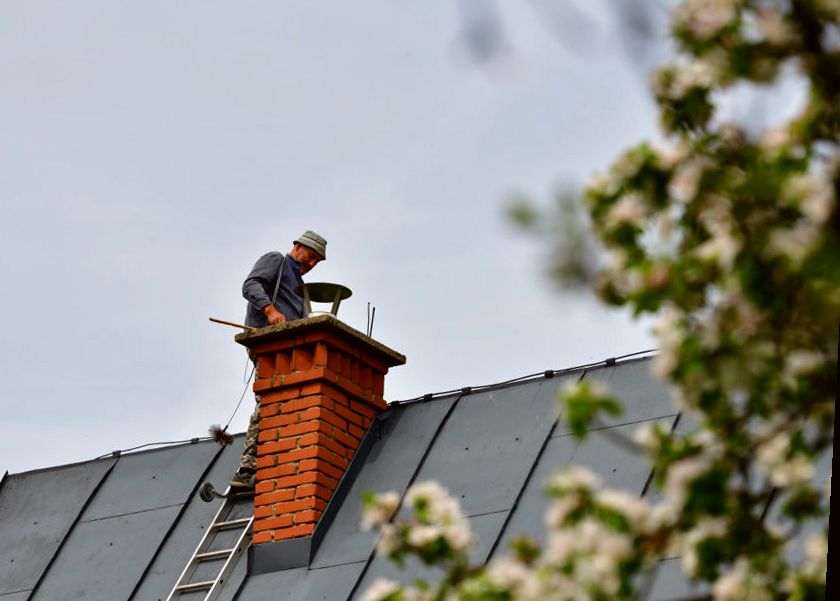 Technician at a chimney on a standing-seam roof